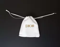 Authentic small white pouch by Dior. Strings pull at top to close bag. DIOR in gold lettering is printed on front.