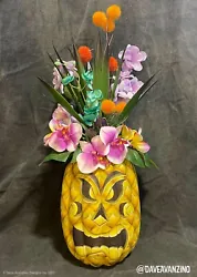 A Tiki Totem face was then painted over the surface to appear as if it was carved into the pineapple. The bottom of the...