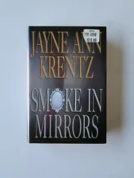 This is a hardcover copy of Smoke in Mirrors by Jayne Ann Krentz, published in 2002 by Penguin Publishing Group. The...