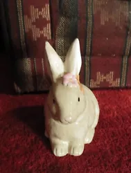 THIS BUNNY IS OFF WHITE IN COLOR. THIS BUNNY HAS TWO FLOWERS BY THE EAR. ONE IS PINK AND THE OTHER IS ORANGE. THE DEPTH...
