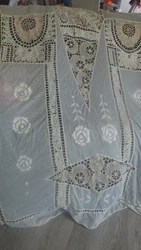Tulle est broderies. 2 petits trous dans sur la tulle rien de méchants les franges sont à démêler. Belle nappe ou...