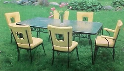 The wrought iron has grape cluster designs, (grapes, leaves, and vines), on the table sides, trim, chair legs and chair...