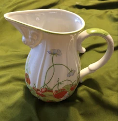 This pitcher is white with strawberry plants.
