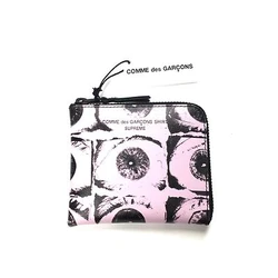 Made of pink genuine leather with allover eye print. Zip-around design with interior slot.