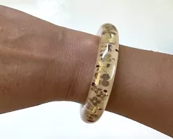 Bracelet Louis Vuitton. Modèle : Inclusions monogrammes dorés. Accessoires : boîte et écrin. Résine couleur :...