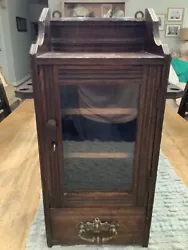 Antique English smoking cabinet with locking glass door. Three shelves are inside and bottom has a drawer. 4 openings...
