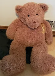 This cute bear would lay or sit on a bed.