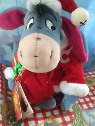 Disney Winnie the Pooh Character Eeyore the donkey. He is dressed for Christmas with a hat and holding a present. At...