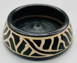 A bowl shaped burner with a wide base and inward inclining straight sides, decorated with black and white designs, and...