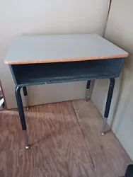 Adjustable student/adult desk with storage compartment underneath. The storage compartment is plastic, the top is wood...
