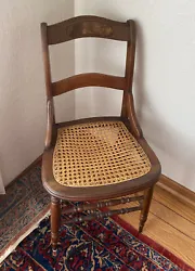 Antique wooden chair with cane bottom. This is a small to medium sized chair. Not suitable for a large person. The cane...