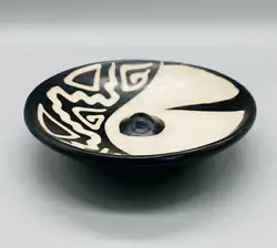 Plate shaped, decorated with black and white designs, and has a hole in the center for placing stick incense. 4 3/4