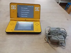 Nintendo DSi XL console jaune et noir avec chargeur officiel.