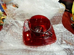 Deep ruby red cup and saucer. the saucer has a ribbed bottom. the cup has a small footed base.