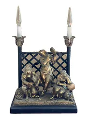 Approximately 18” high 12 1/2” wide 7” deep. Offered is a 2 light Figural lamp with a group playing musical...