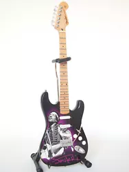 Jimi Hendrix est représenté sur la caisse de la guitare miniature jouant sur une Fender Stratocaster blanche. C’est...