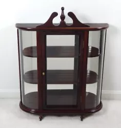 This dark stained wooden piece has a glass door at front and curved glass panels at sides. The interior includes three...