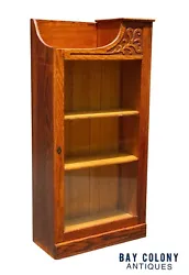 The bookcase has a single glass door with 3 interior shelves. The third shelf is resting in the bottom of the case in...