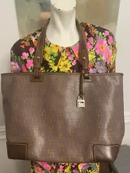 This Dooney and Bourke tote bag features a stylish grey and gold signature monogram design with coated leather trim....