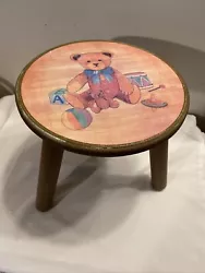 Vintage 3 legged wood stool painted brown with Teddy Bear scene painted on top.  It is 10