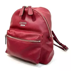 Zip-top small backpack with front zipper pocket. Merlot faux leather on exterior and beige monogram fabric on interior....