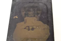 This is an antique tintype of a baby in a chair. The tintype image is dark.