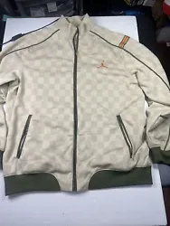 This Nike windbreaker jacket is a must-have for any fashion-forward man. With a cream-colored body and check-patterned...