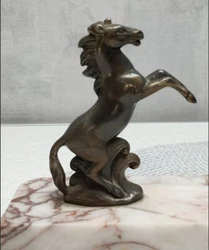Cest une statuette représentant deux chevaux qui sont mis en position face à face avec les pattes avant levées....