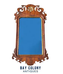 The crest is painted with gold accents and there’s a carved gold border around the mirror. 20TH CENTURY CHIPPENDALE...