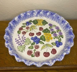 Ruffle edged ceramic pie plate with vibrant hand painted fruits and a blue spongeware edge.