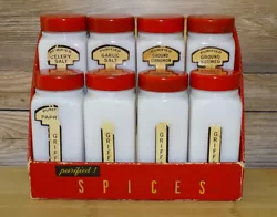 Eight milk glass spice jars with red lids. Four are missing a portion of the spice label.