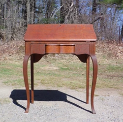 Under the writing surface is a single sculptural dovetailed drawer and rests upon two square legs in the back and two...