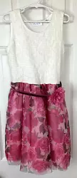 Stretchy white textured top. The skirt is full with a pink rose tulle overlay. Pink belt with a flower accent on the...
