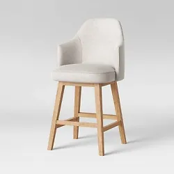 •Upholstered counter stool with a curved back and swivel seat function •Natural wood-finish frame offers a sleek...