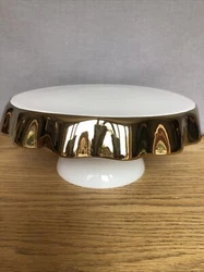 New in box ceramic cake / canapé stand with white base and gold skirt. 8 3/4” diameter 3 3/4”Tall. Box does have...