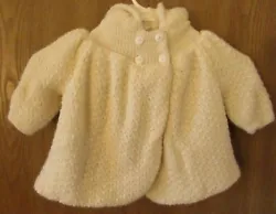 Done in a super soft ivory color, the front has 4 buttons at the neck and then flares out in the swing style.