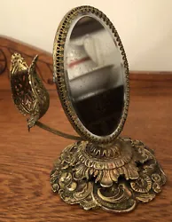 Ornate Oval Vanity Mirror Vintage Gold Metal Base Filigree Frame Tulip Lipstick Holder. Measures 6” high. Mirror is...