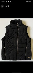 This Calvin Klein puffer vest is the perfect addition to any casual outfit. The black, mid-length vest features a gold...