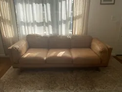 Used tan leather Timber sofa from Article. Originally retails at $1700. Water damage to back of cushions, and small...
