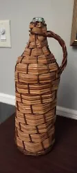 Up for sale a wicker covered wine bottle with handle. The item measures 16.5 tall and 5 3/4 in diameter on the bottom....