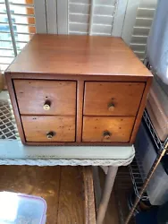 The wooden cabinet has round brass knobs and lots of pretty knots in the wood. It sits squarely on a table. It is fully...