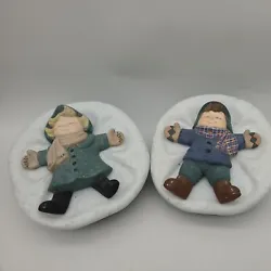 Ceramic bowls are painted green, the lids are white “snow” with a boy and a girl making snow angels.