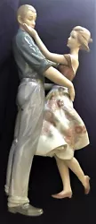 The woman is wearing a bright floral dress with a full flying skirt. The original box (which shows wear and tear from...