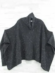 It is a poncho sweater in black with a monks neckline and open side seams. The cut shares a likeness to that of...