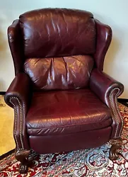 Dark oxblood color faux leather with brass nail trim on arms and carved wooden legs.