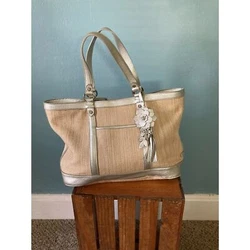 Cole Hann straw woven tote bag pocketbook with silver leather straps and details with 1 snap closure. Inside has 1 zip...