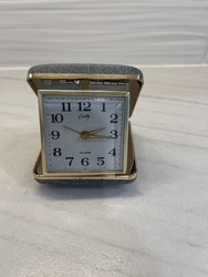 Wind up Bradley travel alarm clock. Fabric covered case, works great! The hinge part is partially attached to the lid.