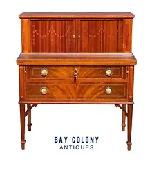 The desk is heavily inlaid and has inlaid tambour doors decorated with festoons of bellflowers. The tambour doors are...