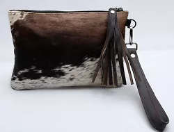 The purse features cowhide on both sides. The inside is silk cloth lined. The wristlet can either be carrier on its own...
