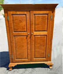 Strong allover tiger maple grain, wooden pin construction, wide board back, and raised panel doors over bracket feet....